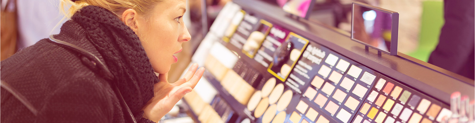 Blog banner featuring close up of blonde woman looking at makeup display in store