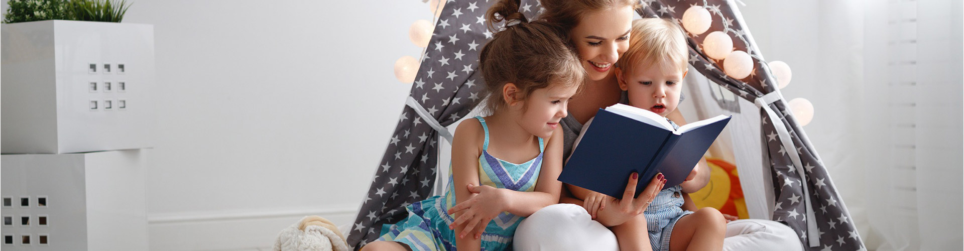 Blog banner featuring mom reading a book to her two small children who are sitting on her lap