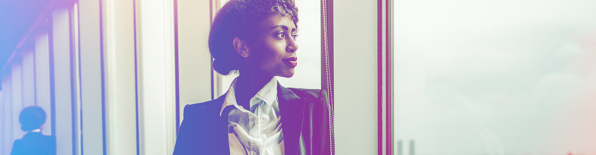 Developing African American Talent in our Industry blog banner featuring professional young black woman in an office hallway looking out a large window with a smile
