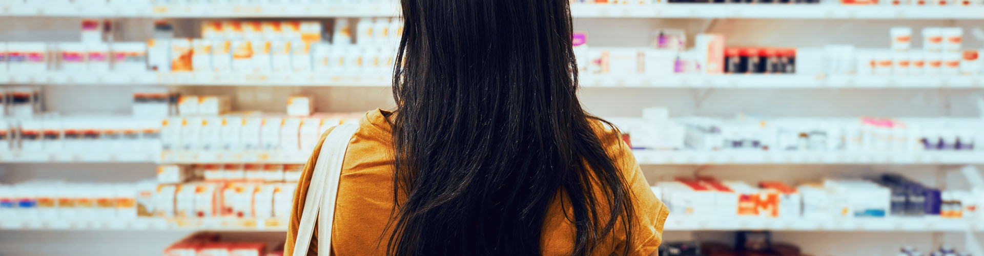 Banner featuring back of woman looking at retail pharmacy shelves